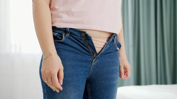 Primer plano de la mujer joven con sobrepeso que no se pone jeans ajustados. Concepto de exceso de peso, obesidad femenina, dieta y problemas de sobrepeso — Foto de Stock