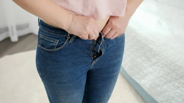 CLOseup di giovane donna sconvolge dopo il montaggio e cercando di abbottonare piccoli jeans. Concetto di sovrappeso, obesità femminile, problemi di dieta e sovrappeso — Foto Stock