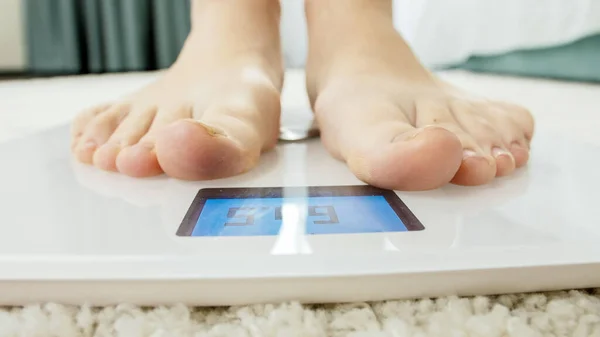 Penutupan kaki wanita berdiri pada skala digital di kamar tidur — Stok Foto