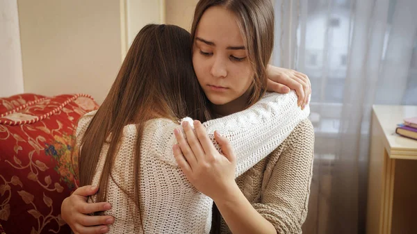 Teenage girl hugging and consoling her crying friend at bedroom. Friends support and teenager depression — Stock Photo, Image