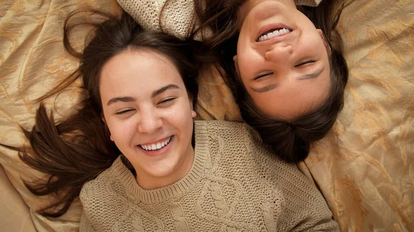 Cámara girando sobre dos chicas adolescentes acostadas en la cama y hablando. Amistad y relación adolescente —  Fotos de Stock