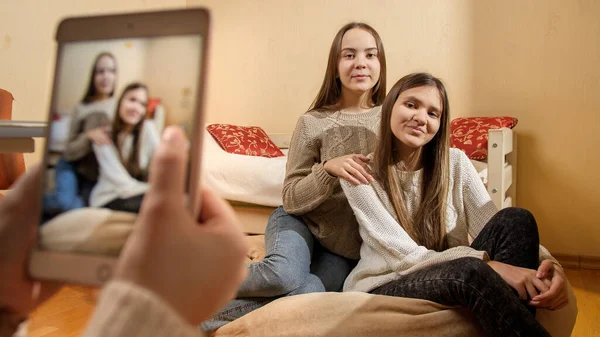 Amigos fotografando fotos de duas meninas adolescentes sorridentes bonitas em casa para o site de mídia social. Comunicação moderna, mídias sociais e gadgets — Fotografia de Stock