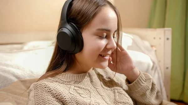 Щаслива усміхнена дівчина розслабляє і слухає музику в навушниках вдома — стокове фото