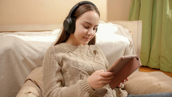 Souriant adolescent fille navigation Internet sur tablette et écouter de la musique dans les écouteurs — Photo
