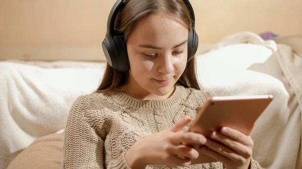 Портрет усміхненої дівчини-підлітка з навушниками за допомогою планшетного комп'ютера та інтернету — стокове фото