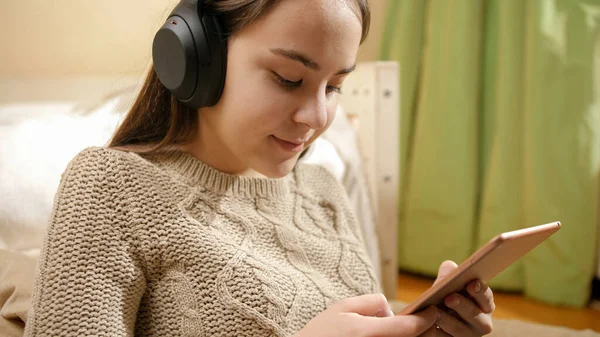 Portrait d'adolescente souriante dans les écouteurs naviguant sur le site de médias sociaux sur tablette — Photo