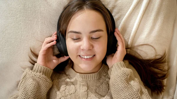 Портрет щасливої усміхненої дівчини-підлітка, що слухає музику і розслабляється в ліжку — стокове фото