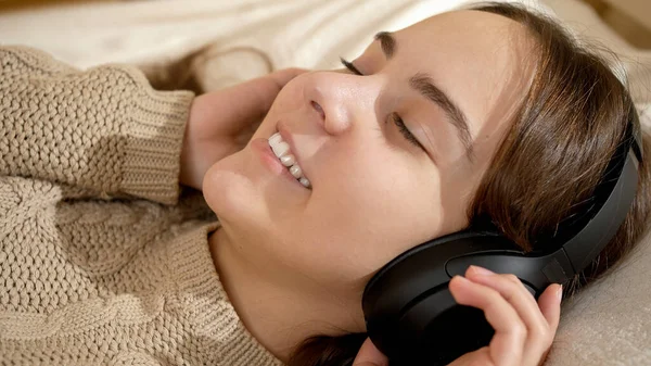 Портрет усміхненої дівчини, яка насолоджується і розслабляється під час прослуховування музики в ліжку — стокове фото