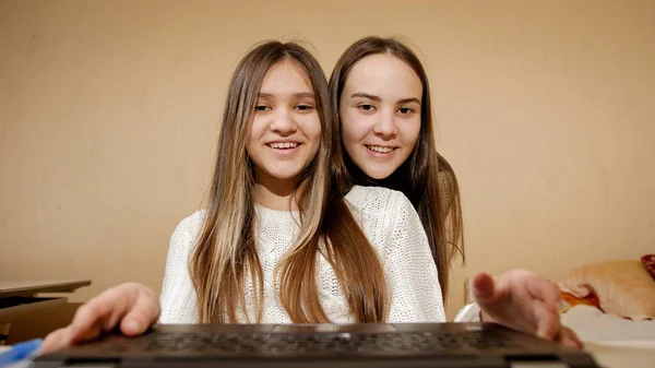 Två leende flickor använder laptop och har online video samtal eller konferens. Fjärrarbete, kommunikation och utbildning — Stockfoto