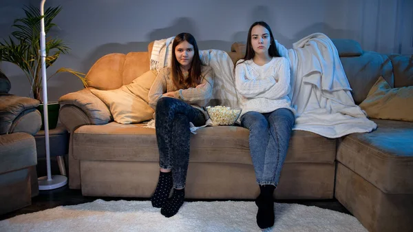 Две девушки сидят на диване в гостиной и смотрят телевизор ночью — стоковое фото