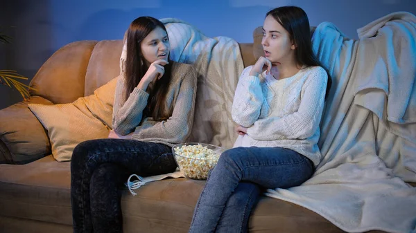Dos chicas hablando y discutiendo películas blancas viendo televisión por la noche —  Fotos de Stock