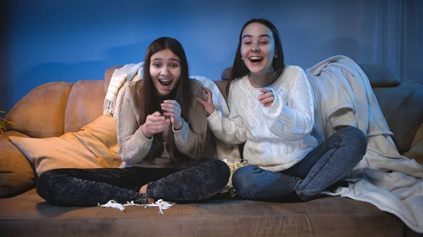 Deux filles souriantes regardant un film drôle ou un programme de télévision et riant sur des blagues — Photo