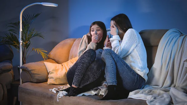 Dos chicas adolescentes cerrando los ojos mientras ven aterrador programa de terror en la televisión por la noche — Foto de Stock