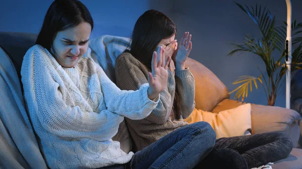 Chicas jóvenes cerrando los ojos y sintiéndose disgustadas mientras ven horror o espectáculo de miedo en la televisión —  Fotos de Stock
