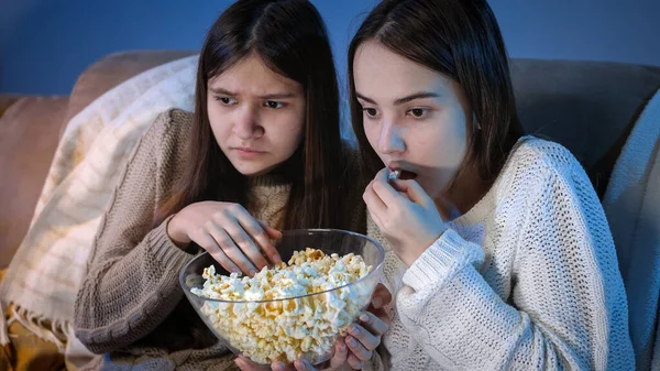 Duas meninas comendo pipocas de tigela grande enquanto assiste filme de terror assustador na TV — Fotografia de Stock