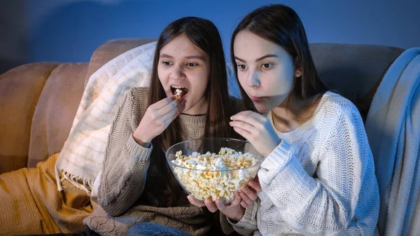 Chicas sonrientes felices disfrutando viendo programas de televisión y comiendo palomitas de maíz por la noche — Foto de Stock