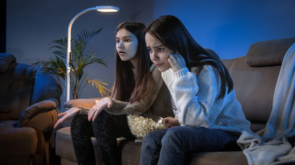 Två upprörda och irriterade flickor tittar på fotbollsmatch på TV på natten — Stockfoto