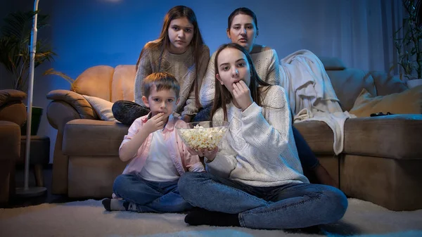 Группа людей ест попкорн во время просмотра фильма или ТВ-шоу в гостиной ночью. — стоковое фото