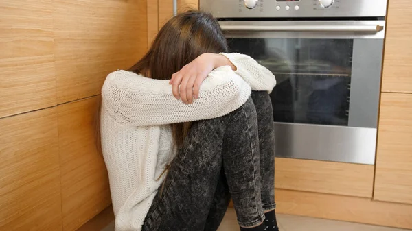 Adolescente deprimida sentada en el suelo en la cocina y llorando. Sentirse solo e incomprendido —  Fotos de Stock