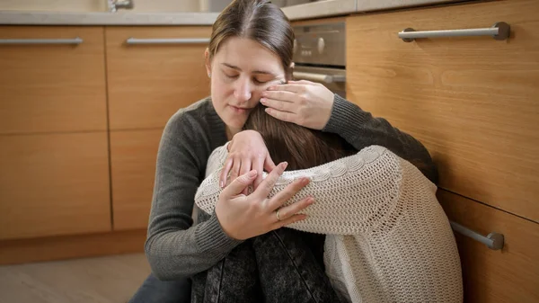 Jonge moeder zit naast huilende dochter en troost haar. Geestelijke problemen en depressie bij tieners — Stockfoto