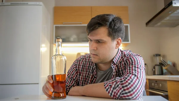 Jovem mulher tomando garrafa de álcool durante o conflito com o marido bêbado na cozinha. Problemas de alcoolismo e dependência — Fotografia de Stock