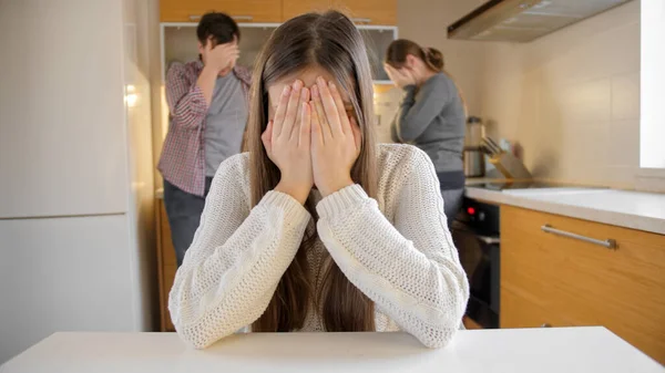 Overstuur meisje huilen en sluiten gezicht met de handen omdat op ruziën en schreeuwen ouders in de keuken. Gezinsgeweld, conflicten en relatieproblemen — Stockfoto