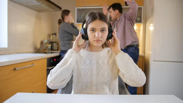 Adolescente mettre des écouteurs pour fermer les oreilles en raison de la dispute et crier parents. Violence familiale, conflits et problèmes relationnels — Photo