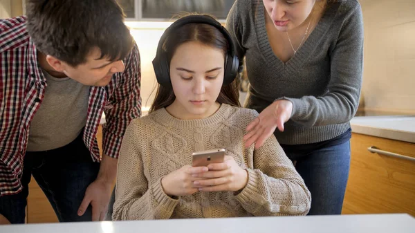 Puberťačka poslouchá hudbu a používá smartphone, zatímco rodiče křičí a hádají se s ní. Rodinné násilí, konflikty a problémy ve vztazích — Stock fotografie