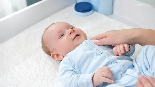 Junge Mutter streichelt ihren kleinen Sohn, der auf dem Schminktisch liegt. Konzept der Hygiene, Babypflege und Gesundheitsfürsorge — Stockfoto