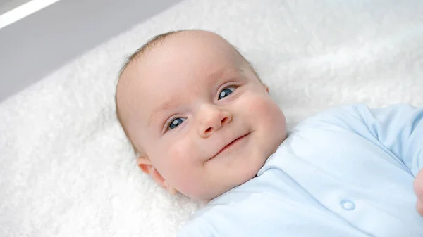 Porträt eines glücklich lächelnden Jungen mit blauen Augen, der auf dem Schminktisch lächelt. Konzept der Hygiene, Babypflege und Gesundheitsfürsorge — Stockfoto