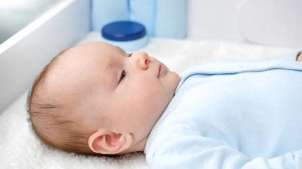 Retrato de bebé lindo con ojos azules acostado y sonriendo en la cámara — Foto de Stock