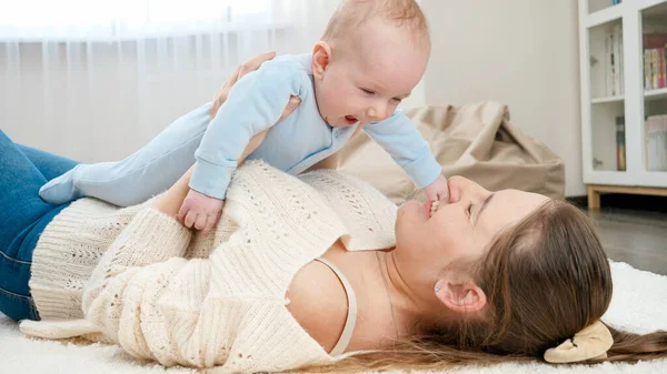 Lindo niño sonriente acostado en la madre y mirándola. Concepto de felicidad familiar y desarrollo infantil — Foto de Stock