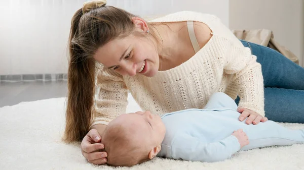 Młoda kochająca matka głaskająca i rozmawiająca ze swoim synkiem leżącym na dywanie w salonie. Pojęcie szczęścia rodzinnego i rozwoju dzieci — Zdjęcie stockowe