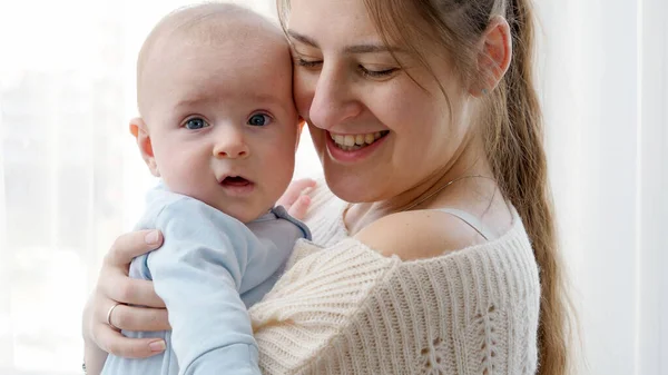 Retrato de feliz madre sonriente abrazando a su pequeño hijo con ojos azules —  Fotos de Stock