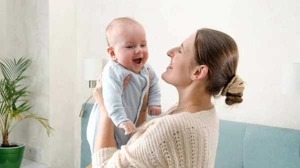Feliz rindo e sorrindo menino olhando para a mãe enquanto ela está segurando e sacudindo-o. Conceito de felicidade familiar e desenvolvimento infantil. — Fotografia de Stock