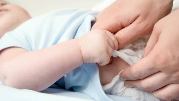 Primer plano de la madre despegando y cambiando pañales desordenados de su pequeño bebé acostado en la cuna. Concepto de padre, higiene del bebé y desarrollo infantil. — Foto de Stock