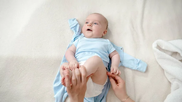 Lindo niñito acostado en la cama mientras su madre le cambia los pañales — Foto de Stock