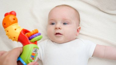 Ebeveynin küçük bebekle oynadığı ve bebek çıngırağı salladığı görüntüler. Bebek eğitimi ve gelişimi kavramı