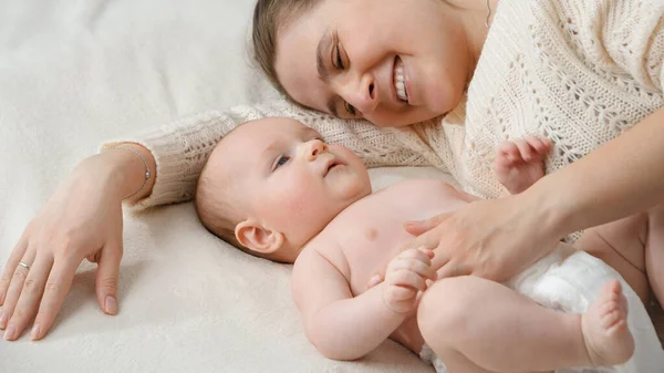 Cute little baby boy and smiling mom lying on bed in bedroom — Stock Photo, Image