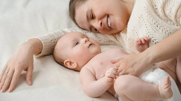 Carino piccolo bambino ragazzo e sorridente mamma sdraiato su letto in camera da letto — Foto Stock