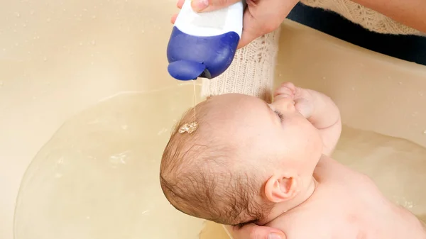 Anne şampuan sürüyor ve küçük oğlunun kafasını banyoda yıkıyor. Ebeveynlik, bebek bakımı ve sağlık hizmetleri kavramı. — Stok fotoğraf