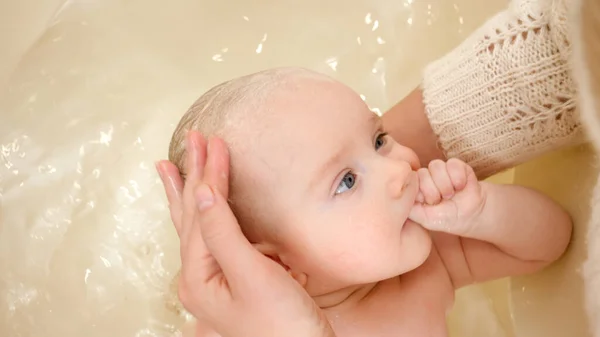 Cute little baby boy sucking finger while mother washing him in bath. Concept of parenting ,baby care and healthcare — Stock Photo, Image