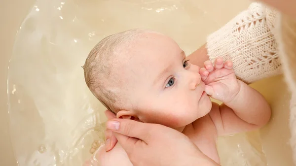 Mały chłopiec ssać palec podczas matka myć jego w kąpiel — Zdjęcie stockowe