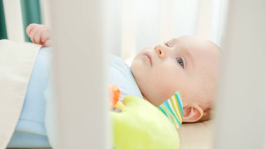 Beşikteki oyuncakla oynayan küçük bebeğe tırabzandan bak. Ebeveynlik kavramı, aile mutluluğu ve bebek gelişimi