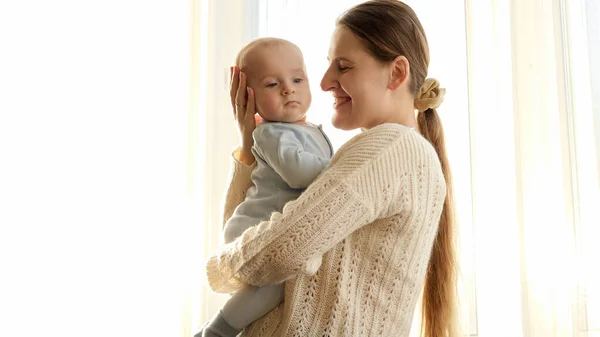 Młoda matka przytula i uśmiecha się do swojego synka w świetle zachodu słońca. Pojęcie szczęścia rodzinnego i rodzicielstwa — Zdjęcie stockowe