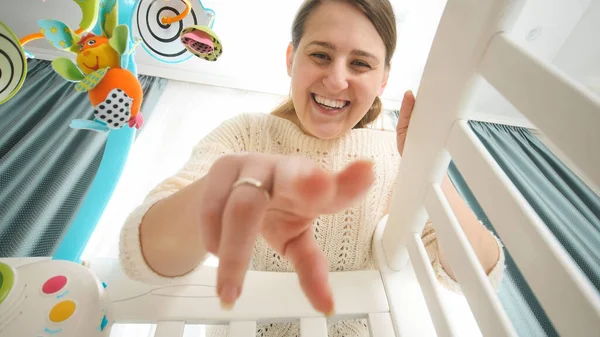 Portret van een vrolijke lachende vrouw die speelt en kijkt naar haar pasgeboren baby in bed, concept van ouderschap, gezinsgeluk en ontwikkeling van de baby. — Stockfoto