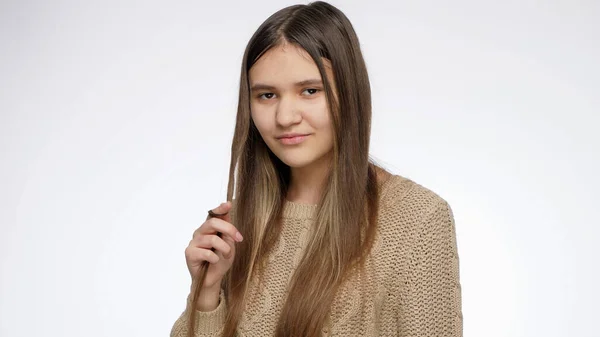 Menina encantadora bonita torcendo cabelos longos no dedo e sorrindo na câmera — Fotografia de Stock