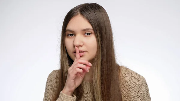 Linda chica sonriente sosteniendo el dedo en la boca en gesto shhh después de contar el secreto — Foto de Stock