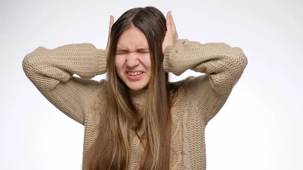 Muchacha molesta de ruido fuerte cerrando sus oídos con las manos sobre el fondo blanco del estudio — Foto de Stock