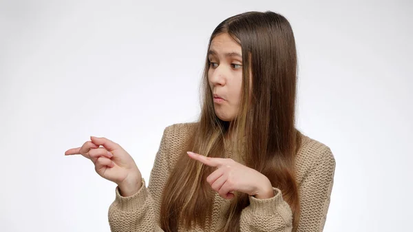 Porträtt av tonåring flicka reklam och peka med fingret på hennes sida över vit bakgrund. Placera din produkt eller objekt. Mall för reklam. — Stockfoto